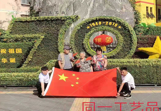 北京游客在植物綠雕國慶綠雕前舉國旗合影 北京游客在植物綠雕國慶綠雕前舉國旗合影